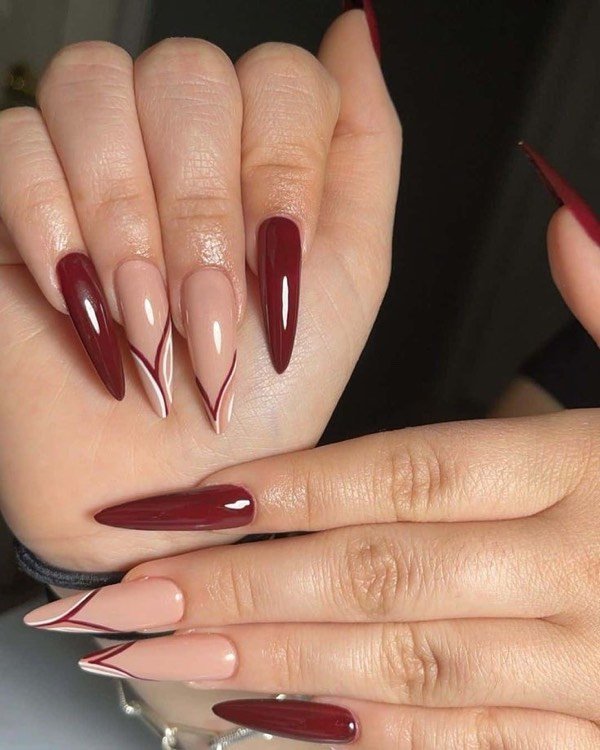 Burgundy stiletto nails with a nude outline design